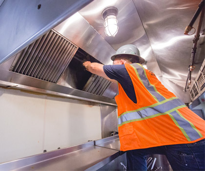 Worker performing kitchen hood cleaning